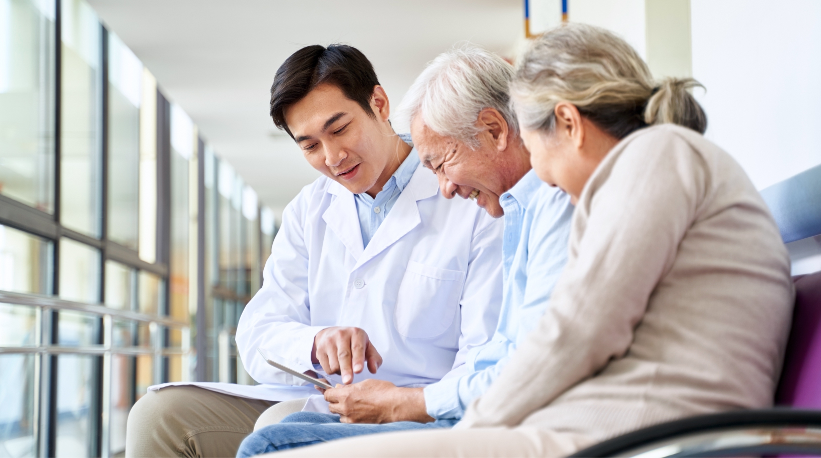 Elderly couple looking at ipad with doctor.